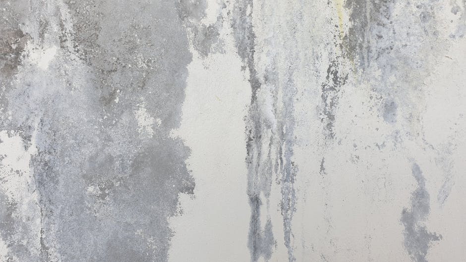 Close-up image of a wooden surface with visible cracks, scratches, and uneven texture, showing signs of wear and damage. The surface appears aged, with dull coloration and some dust particles present.
